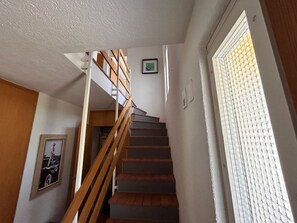 A staircase with wooden railings leading to an upper floor, a framed picture on the wall, and a window with blinds. - Solaria 31 Ferienhaus, Dusche oder Bad, WC 5 1/2- Ferienhaus by Interhome (Davos)