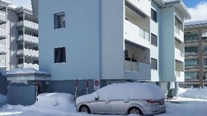 Un edificio a più piani con un parcheggio coperto di neve.