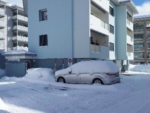 Ein mehrstöckiges Gebäude mit einem parkähnlichen Bereich, bedeckt von Schnee.