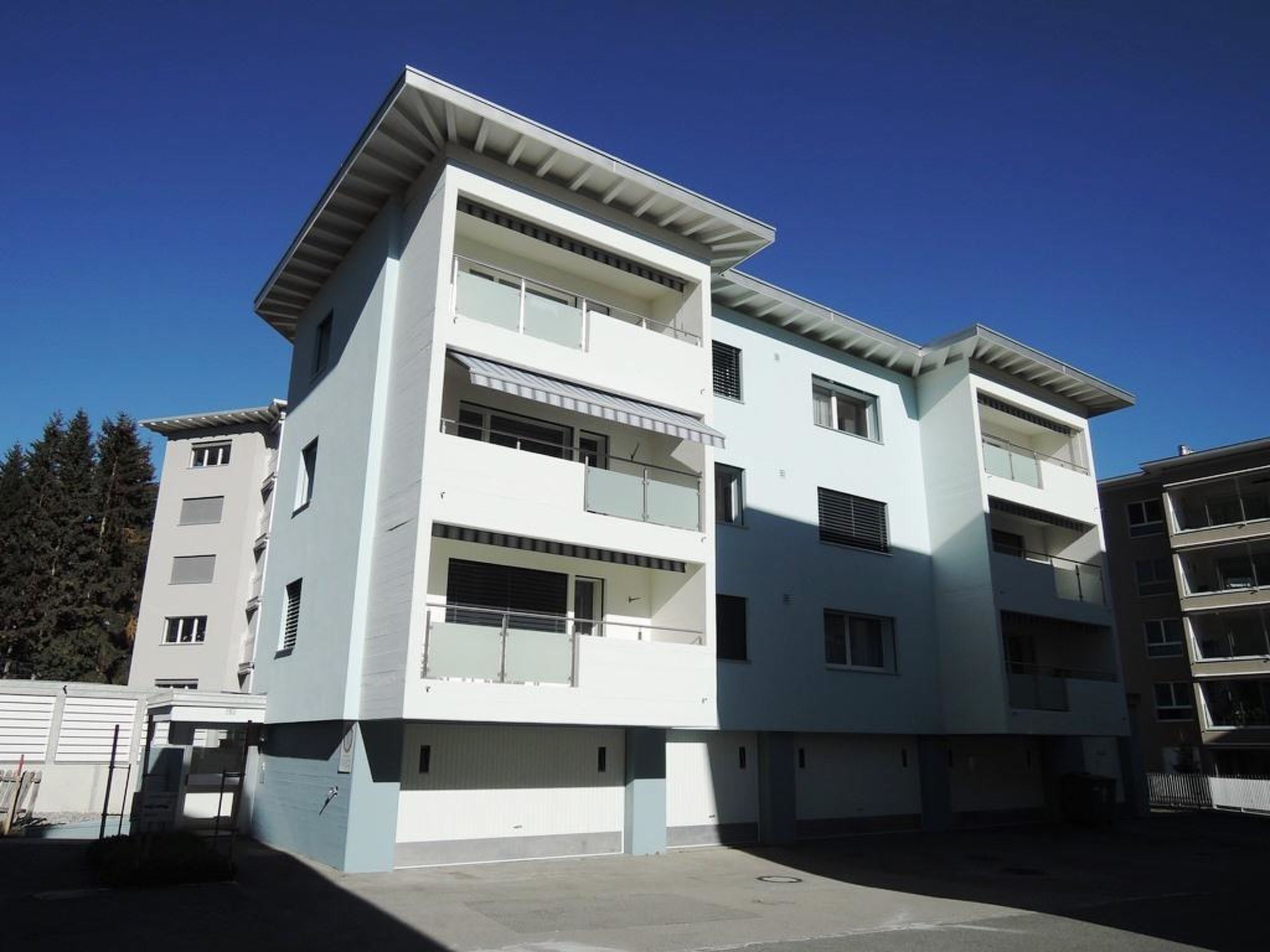 A multi-story building with balconies, large windows, and a flat roof.