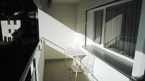 Un balcone con tavolo e sedie, una finestra e vista sugli edifici.