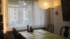 Ein Essbereich mit Tisch, Stühlen, einer Hängeleuchte, einem Fenster mit durchscheinenden Vorhängen und einer Stern-Dekoration an der Wand.