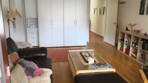 Ein Wohnzimmer mit einer Couch, einem Couchtisch, einem Bücherregal und einem Kleiderschrank.