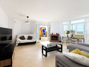 A living room with a sofa, coffee table, TV, fireplace, and large windows. - La samba beachfront by Interhome (Rincón de la Victoria)