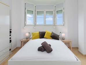 A neatly arranged bedroom with a bed, two bedside tables, a nightstand, a window with blinds, and a wardrobe. - La samba beachfront by Interhome (Rincón de la Victoria)