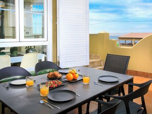 Een eettafel met ontbijtartikelen, stoelen en uitzicht op de lucht.