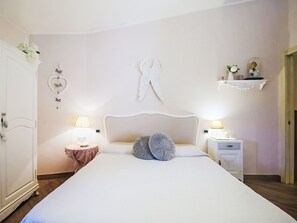 A bedroom with a bed, two bedside tables, a wardrobe, decorative wall art, and a shelf with items. - Ricordi by Interhome (Moneglia)