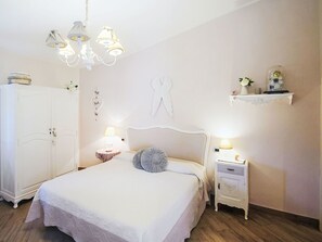 A bedroom with a bed, a wardrobe, a chandelier, bedside lamps, and wall decorations. - Ricordi by Interhome (Moneglia)