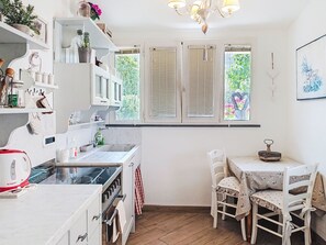 A kitchen with white cabinets, a stove, a sink, and a dining area with a table and chairs. - Ricordi by Interhome (Moneglia)