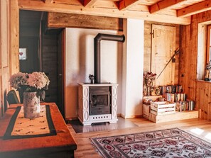 A wooden interior with a fireplace, a dining table with a vase of flowers, and a bookshelf.