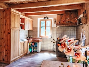 A rustic kitchen with wooden cabinets, a tiled backsplash, and a window providing natural light.