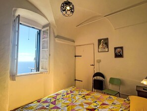 A bedroom with a bed, a window with a view, a door, a chair, and a wall-mounted lamp. - Risorgimento Apartment by Interhome (Cipressa)
