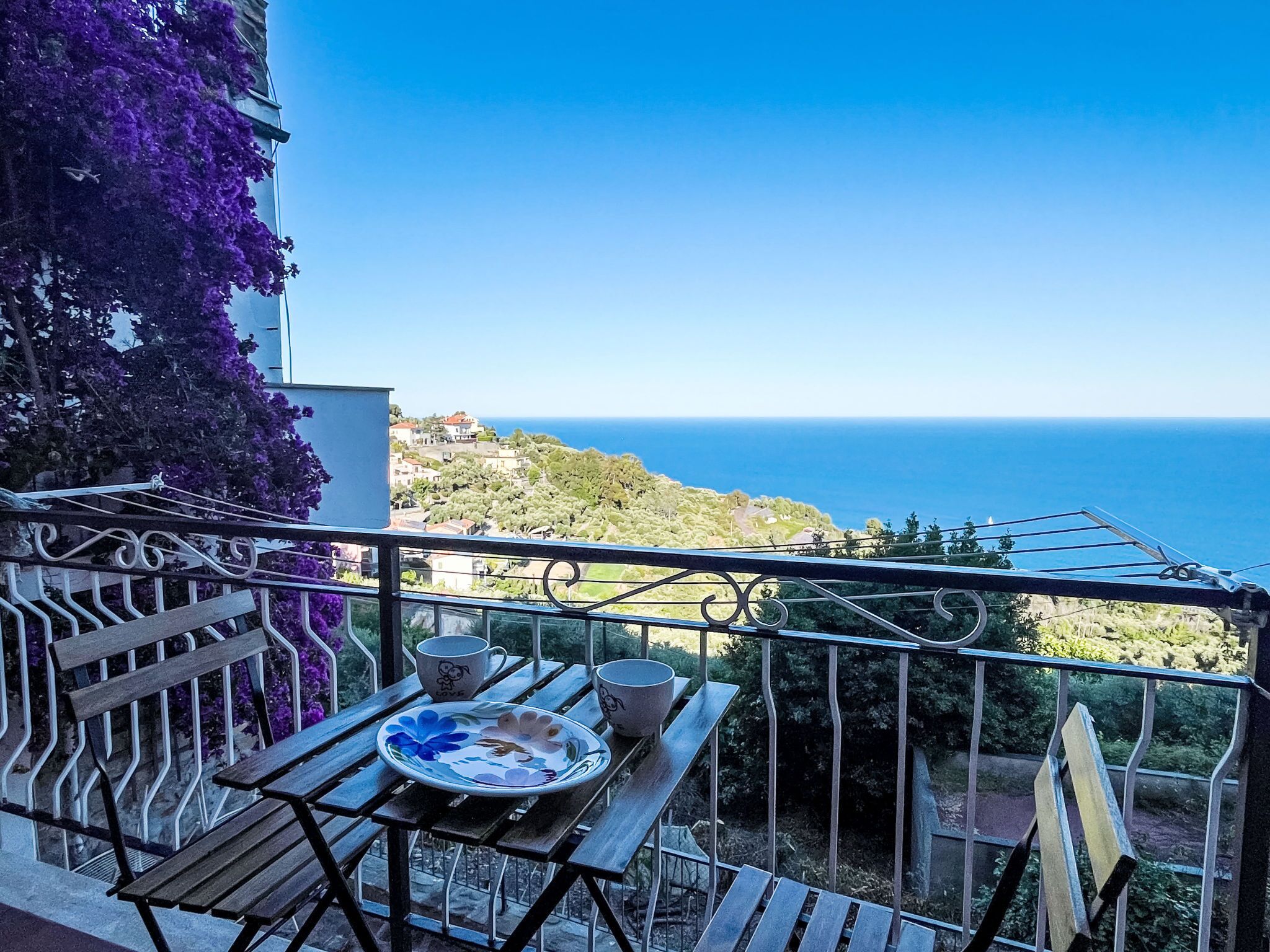 Ein Balkon mit Tisch, Stühlen und Blick auf das Meer.