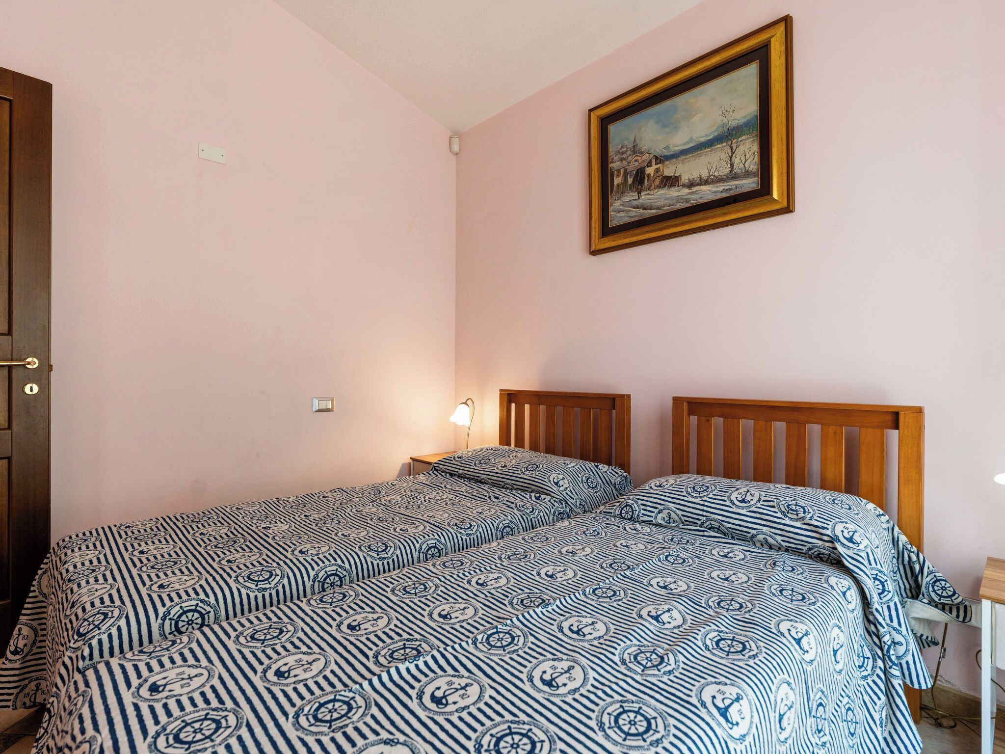 A bedroom with a bed, a nightstand, a lamp, and a painting on the wall.