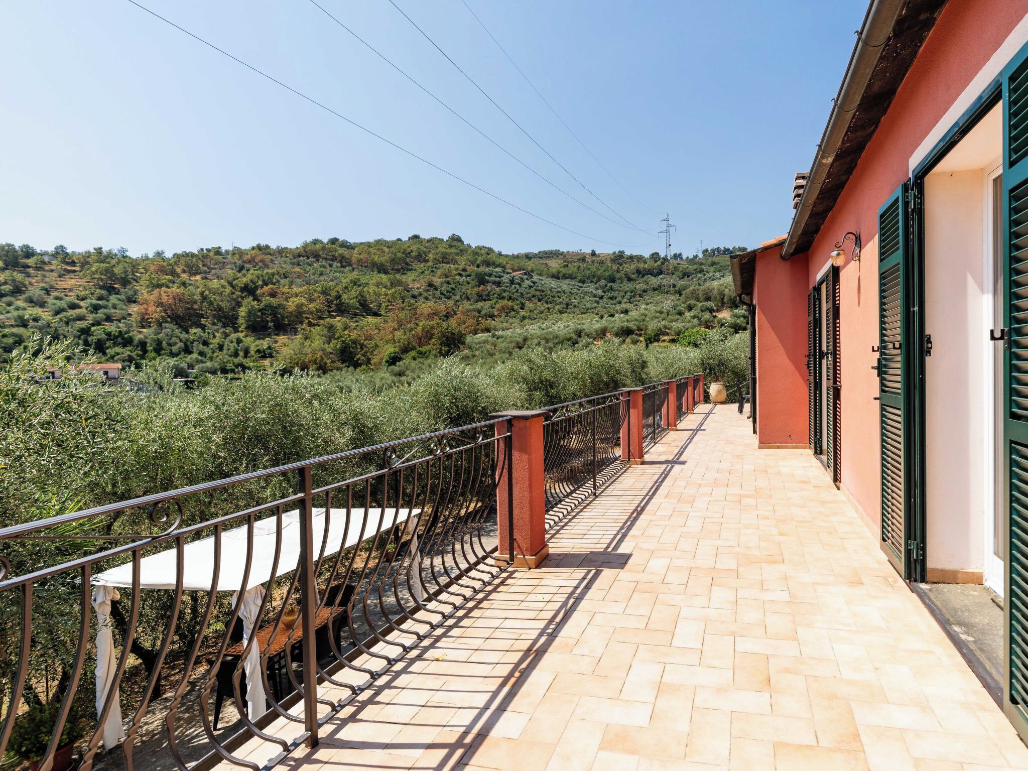 Ein Balkon mit Metallgeländer und Blick auf eine hügelige Landschaft.