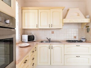 A kitchen with white cabinets, a microwave, a sink, and a stove. - Orto di Silvia by Interhome (Torrazza)