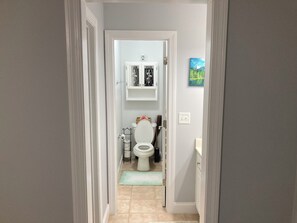 A hallway leading to a bathroom with a toilet, a cabinet with decorative items, and a painting on the wall. - WOW! This room is FABULOUS! WOW again: so is the house. Enjoy your stay (Braselton)