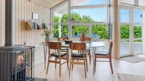 A dining area with a round table, chairs, a fireplace, and large windows offering a view of greenery. - "Skakke" - 350m to the fjord by Interhome (Vestervig)