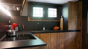 Una cocina moderna con estufa integrada, un fregadero y un ventanal sobre la encimera.