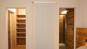 Et soveværelse med en seng, et træhovedgærde, en radiator og et skab med hylder.