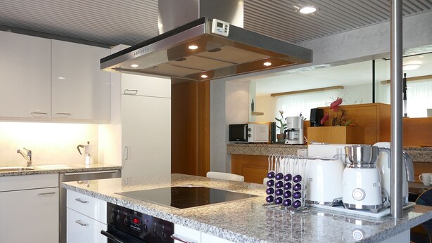 Una cocina moderna con horno empotrado, cafetera y enfriador de vino.