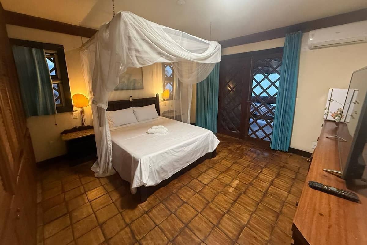 Ein Hotelzimmer mit einem Bett, einem Nachttisch, einer Lampe, einem Fernseher und einem Holzboden.