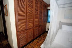 A hotel room with a large wooden wardrobe, a bed with white bedding, and a tiled floor. - Pousada Rosa dos Ventos (Porto Seguro)