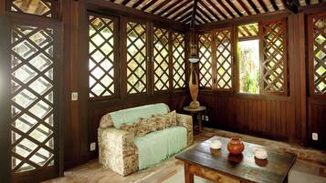 A room with a wooden ceiling, a sofa with floral upholstery, a table with candles, and a lattice window design.
