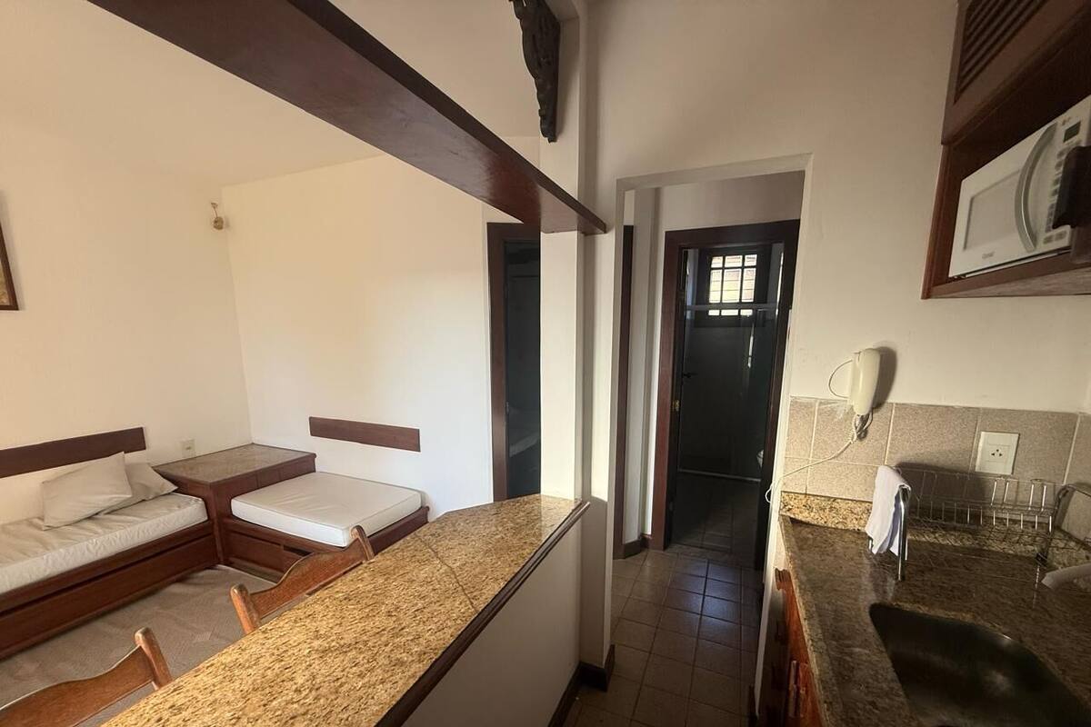 Ein kompaktes Zimmer mit Küchenzeile, einer kleinen Essecke und einer Tür zu einem Badezimmer.