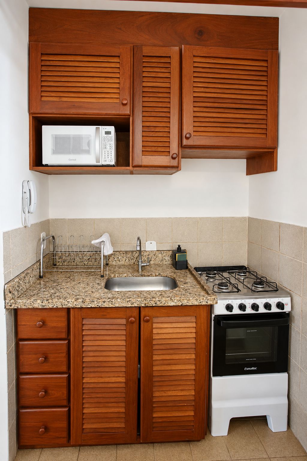 A compact kitchen with wooden cabinets, a microwave, a gas stove, and a built-in oven.