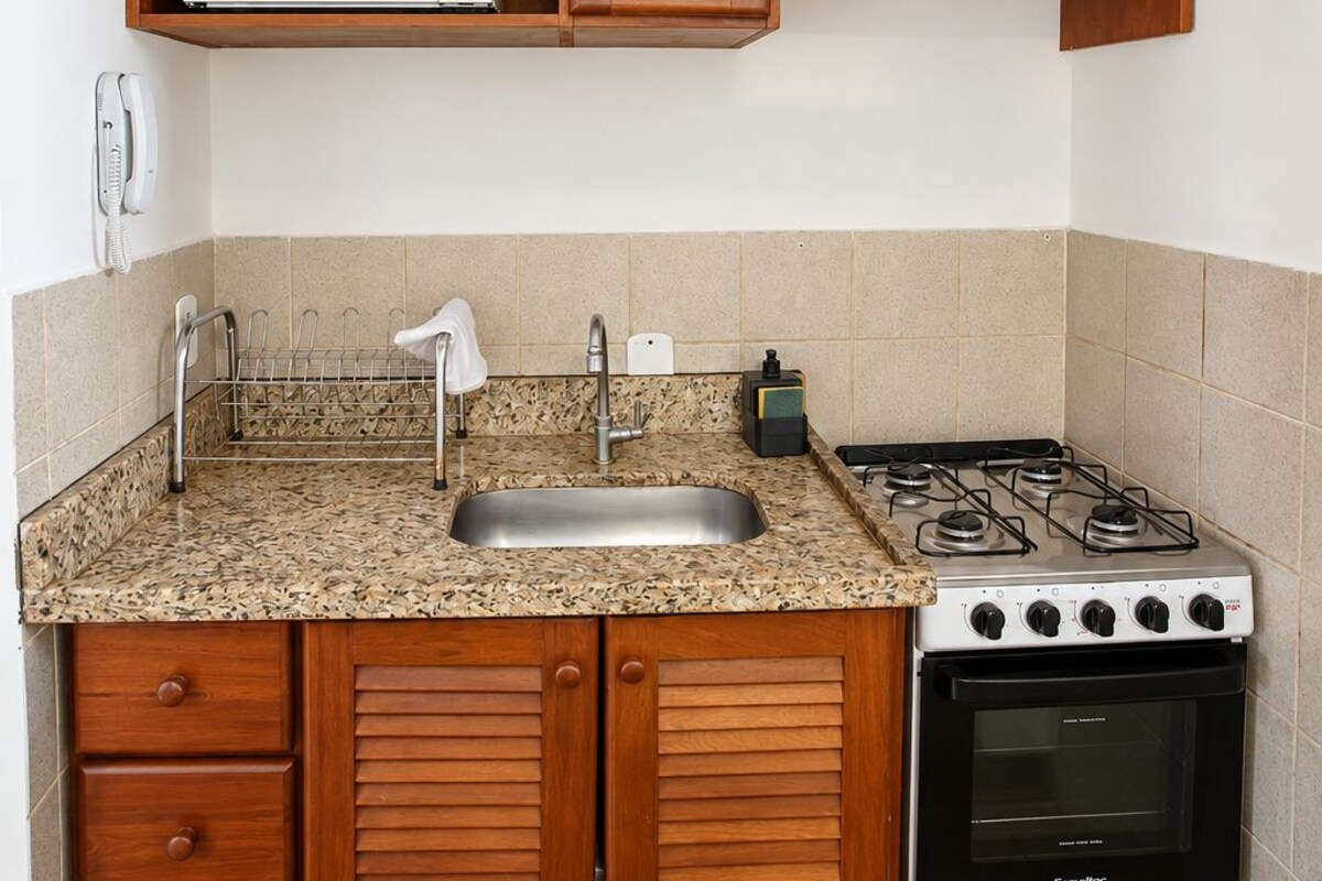 A compact kitchen with wooden cabinets, a microwave, a gas stove, and a built-in oven.