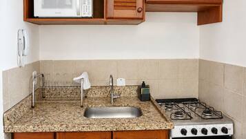 A compact kitchen with wooden cabinets, a microwave, a gas stove, and a built-in oven.