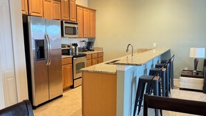 A modern kitchen with wooden cabinets, stainless steel appliances, and a granite countertop. - Lake View Private Pool Townhome - Sleeps 10 (Kissimmee)