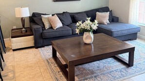 A living room with a sofa, a coffee table, a lamp, a picture frame, and a rug. - Lake View Private Pool Townhome - Sleeps 10 (Kissimmee)