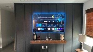 A modern living room with a mounted TV displaying a Smart Hub interface, a wooden console table, and a sofa.