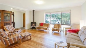 Ein Wohnzimmer mit Kamin, Holzboden und großen Fenstern.