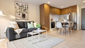 A modern living room with a sofa, coffee table, and a dining area with chairs.