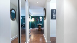 A hallway with wooden flooring, a dining area with a table and chairs, and a wall with framed pictures. - Heart of Corydon (Winnipeg)