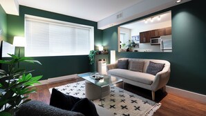 A modern living room with a sofa, coffee table, and a view into the kitchen. - Heart of Corydon (Winnipeg)