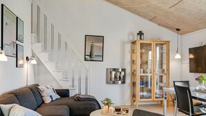Una sala de estar moderna con un sofá, una mesa de centro y un comedor con un armario y sillas.