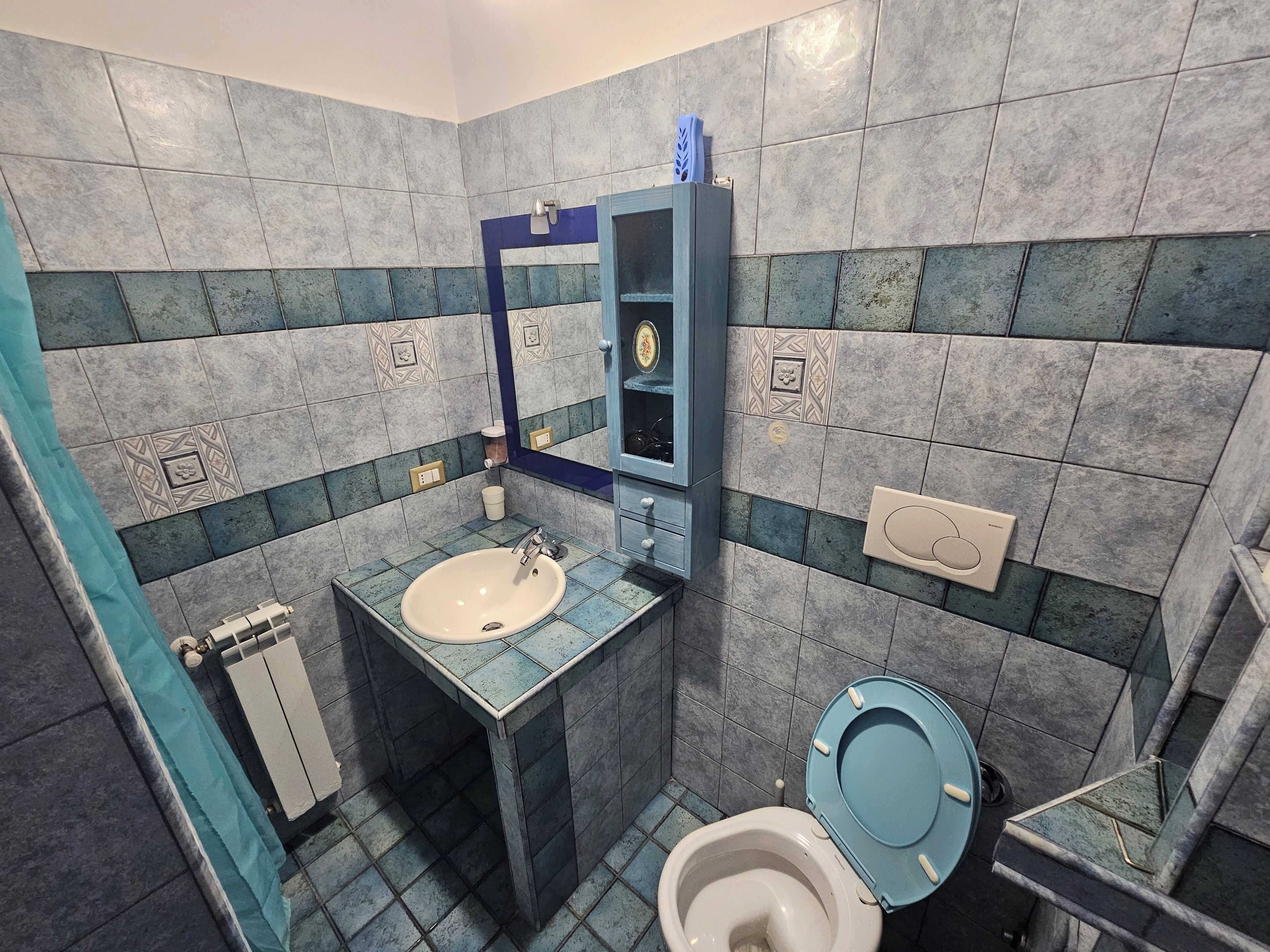 A bathroom with a sink, toilet, and mirror.
