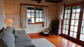 Una habitación con sofá, una silla, una ventana y una puerta.