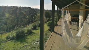 Una hamaca en una cubierta de madera con vista a un paisaje exuberante.
