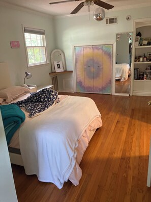 Ein Schlafzimmer mit einem Bett, einem Deckenventilator, einem Fenster und einem Kleiderschrank.