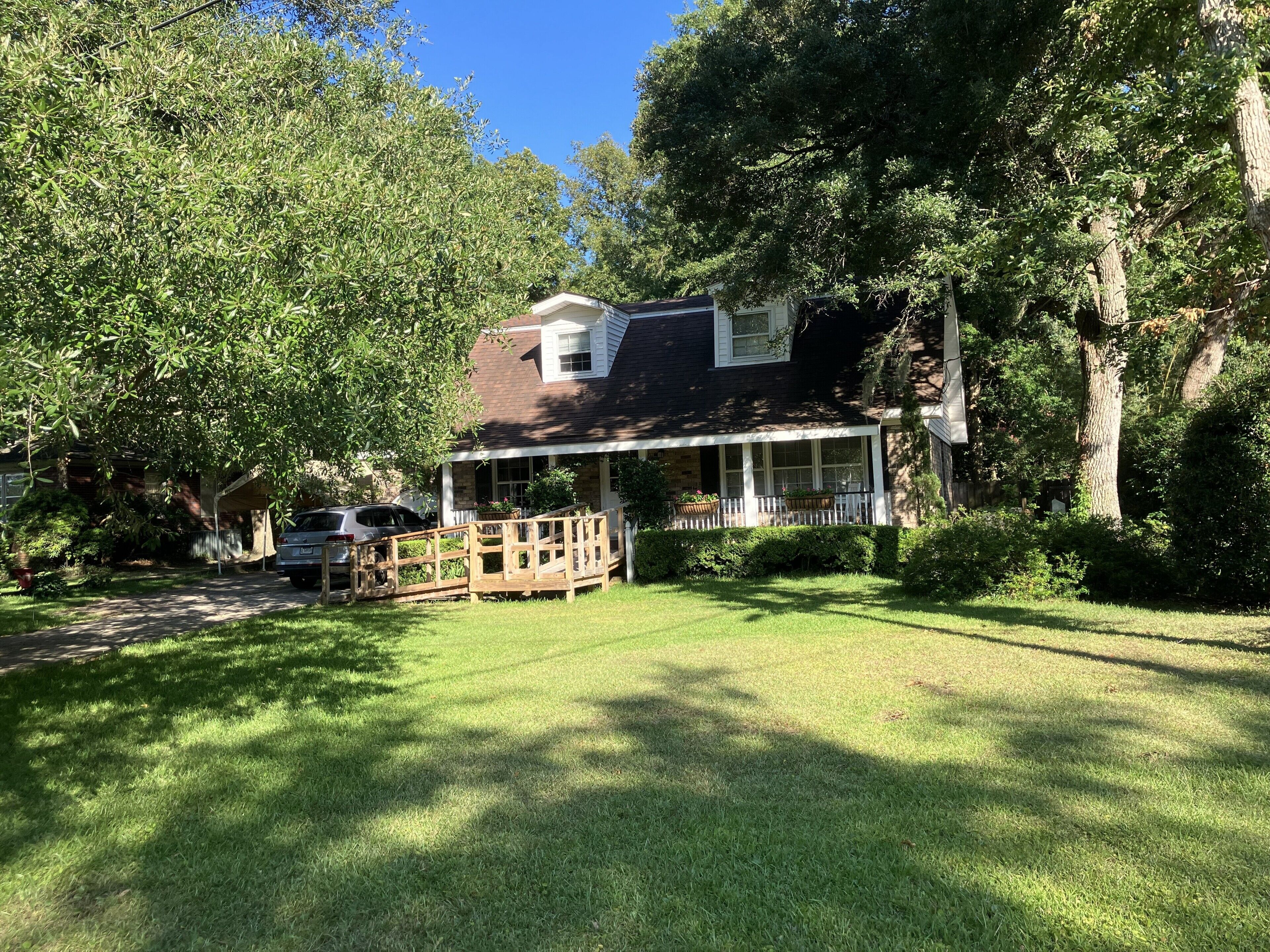 A house with a covered porch, a lawn, and trees.