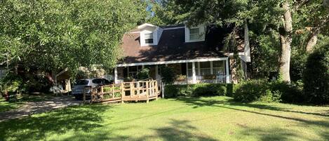 A house with a covered porch, a lawn, and trees.