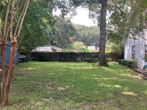 A residential backyard with a grassy lawn, a wooden deck, and a house with a shed. - Southern charm - two bedrooms close to the beach and to Charleston! (Mount Pleasant)
