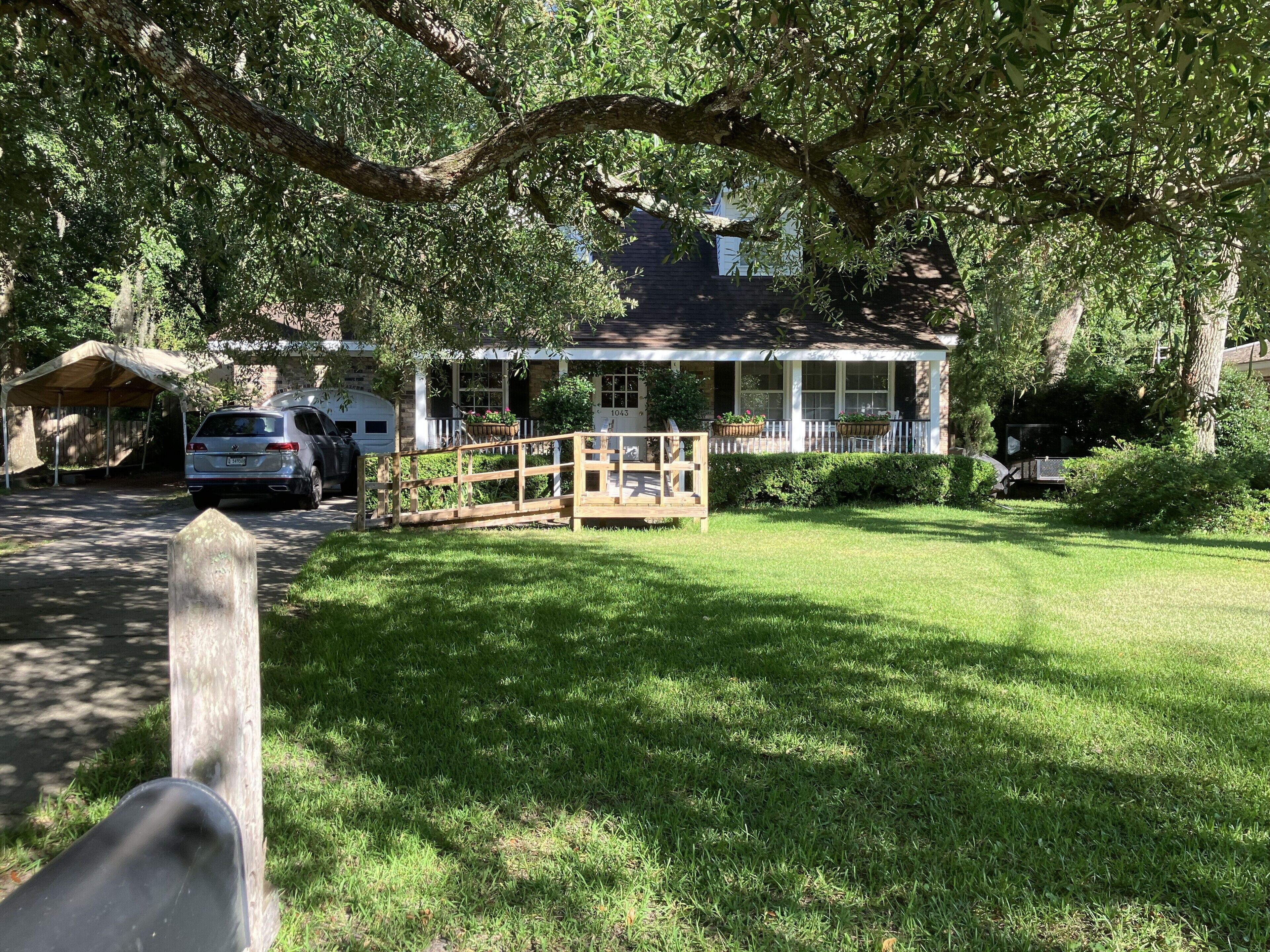 A house with a covered porch, a wooden fence, and a grassy yard.