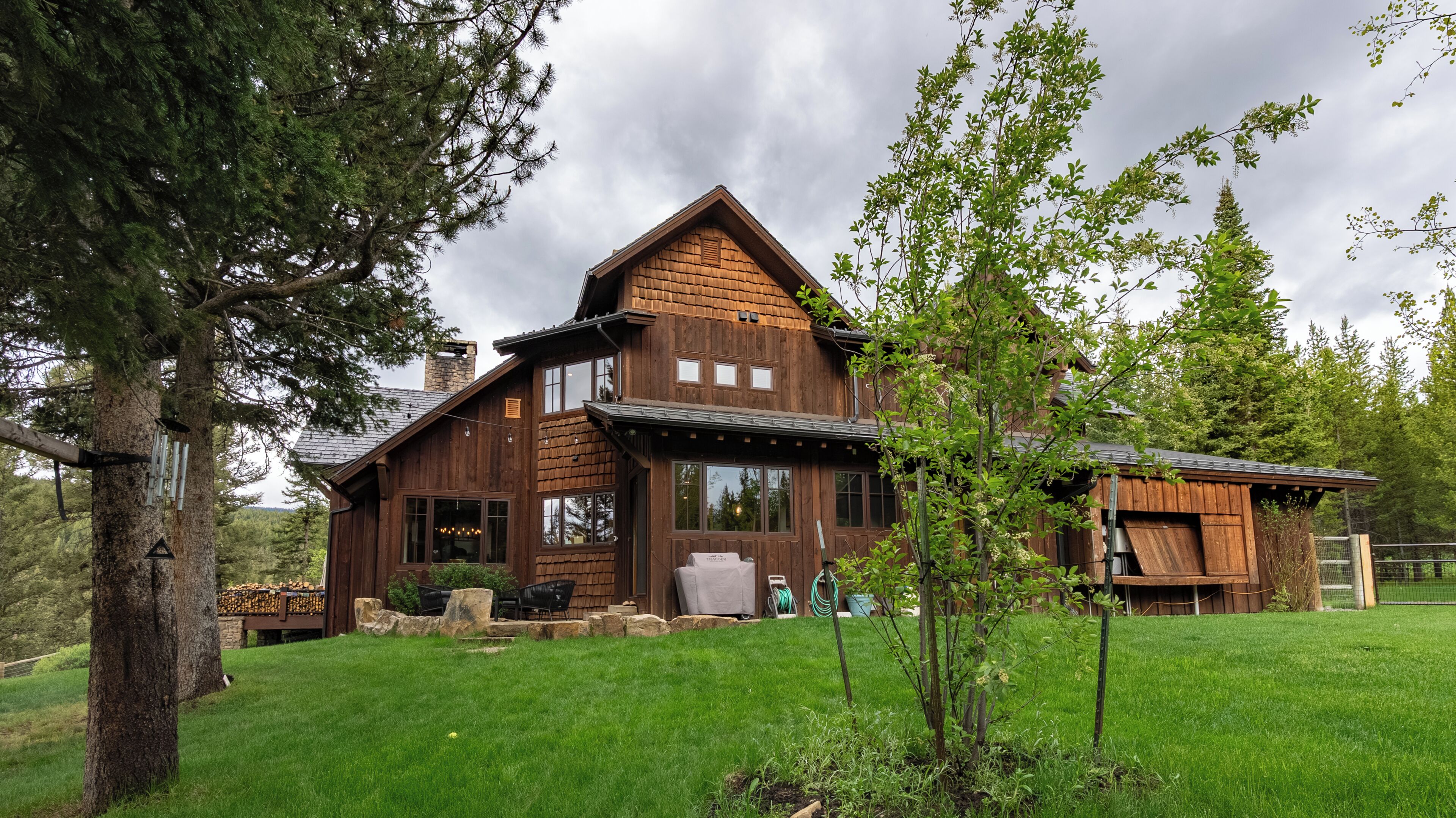 A wooden cabin with a large deck, stone steps, and a small outdoor kitchen area.