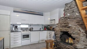 Une cuisine moderne avec des armoires blanches, une cheminée en pierre et une échelle en bois.